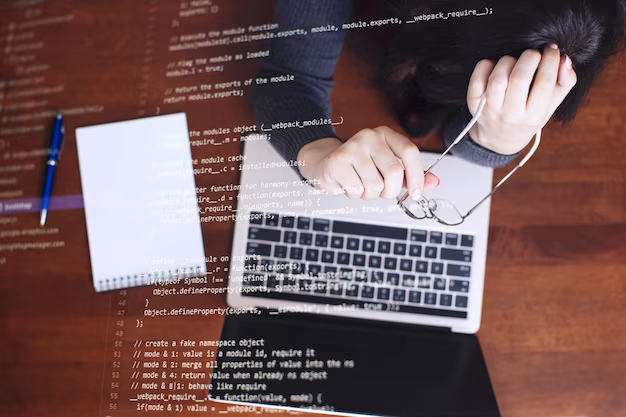 A girl sits in front of a computer and holds glasses in her hands, top view